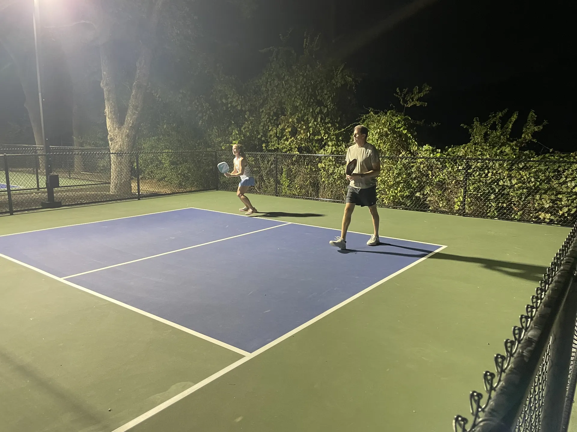 Playing pickleball under the lights at night at Heights Pool